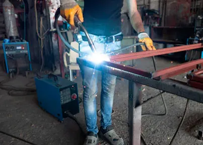 Herrero utilizando máquina para soldar en estructura de acero