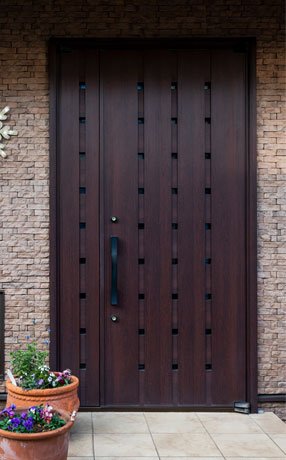 Puerta de herrería y madera de color café instalada en la entrada principal de una casa