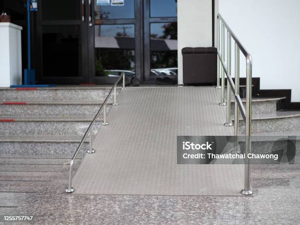 Rampa elaborada de lámina de acero antiderrapante con barandal en la entrada de un edificio 
