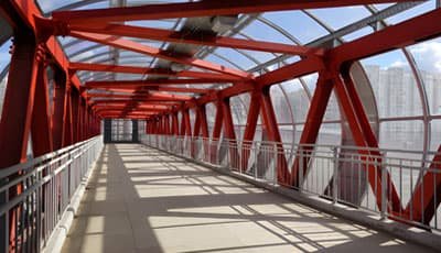 Puente peatonal con una armadura de color rojo fabricada con acero estructural